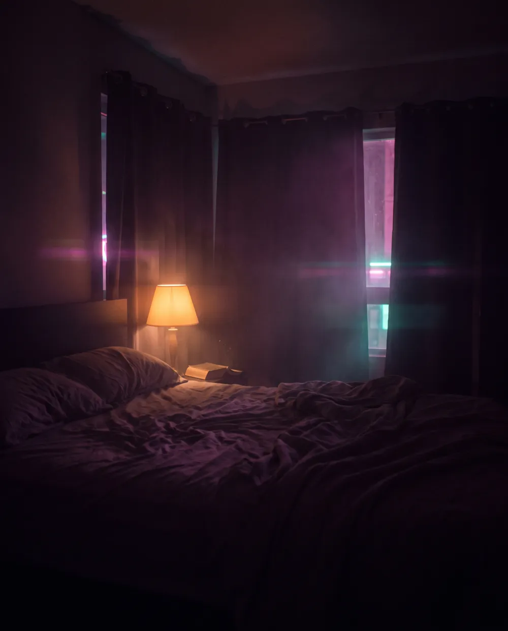 A dark bedroom with linen sheets in deep shadow and soft magenta neon seeping around the curtain edge